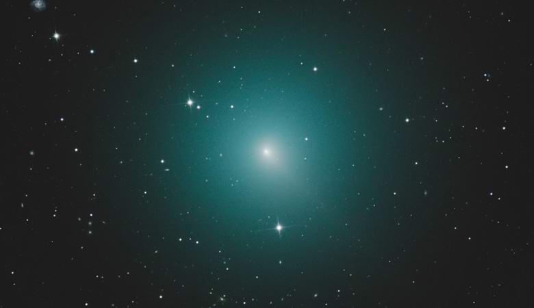 A greenish comet moves toward the Earth, which is already visible with the naked eye